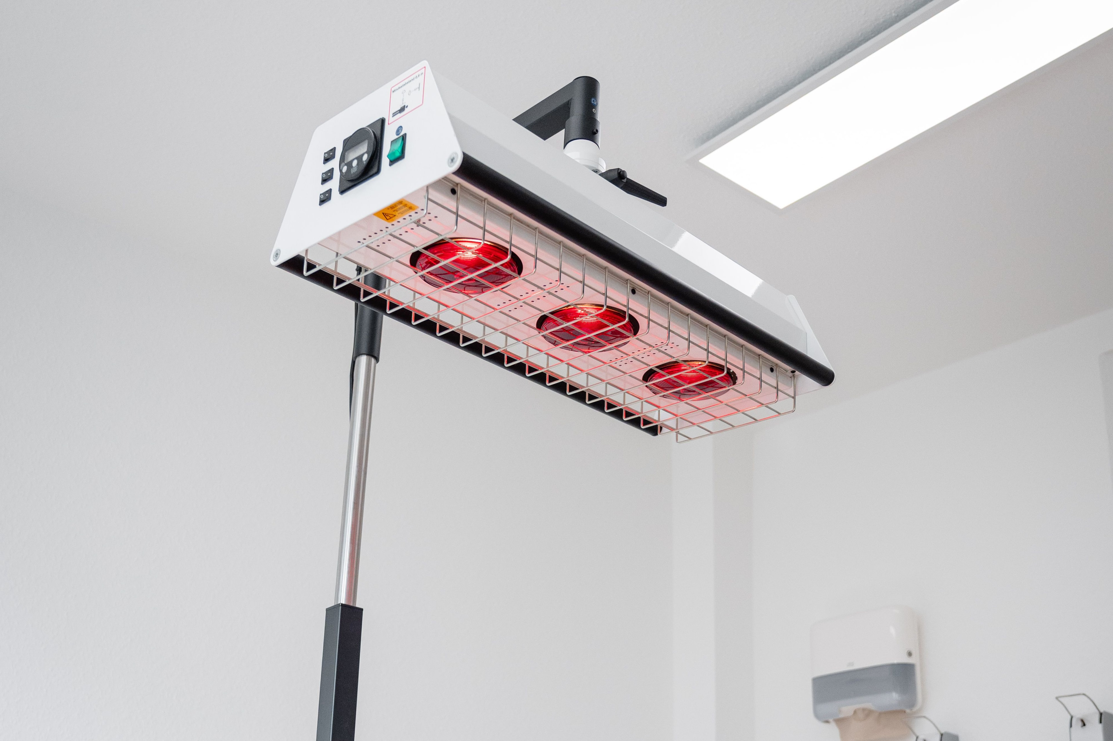 Patient liegt in Bauchlage unter einem Heißluftgerät zur Wärmetherapie im Rahmen der physiotherapeutischen Behandlung in Köln